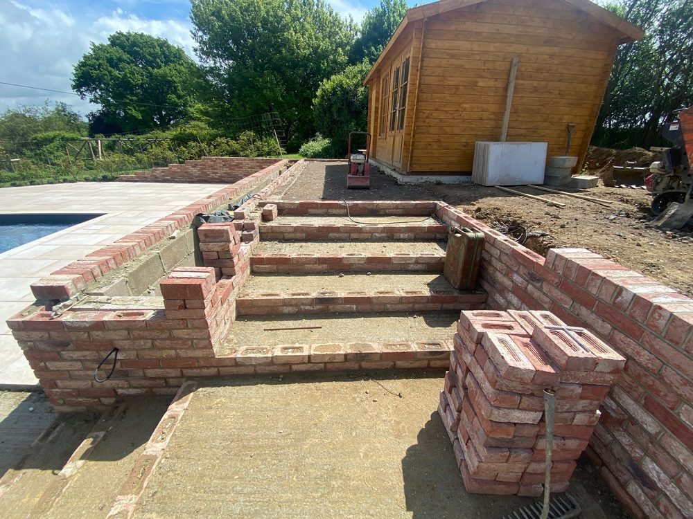 Brick garden walls and steps beside a pool